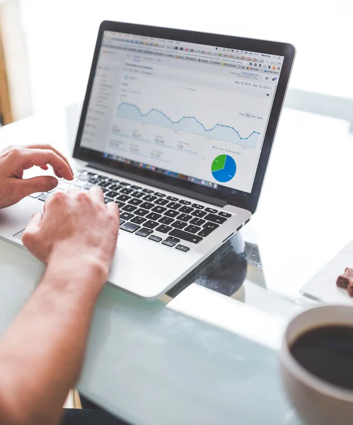 Analyzing data on laptop with coffee cup nearby.